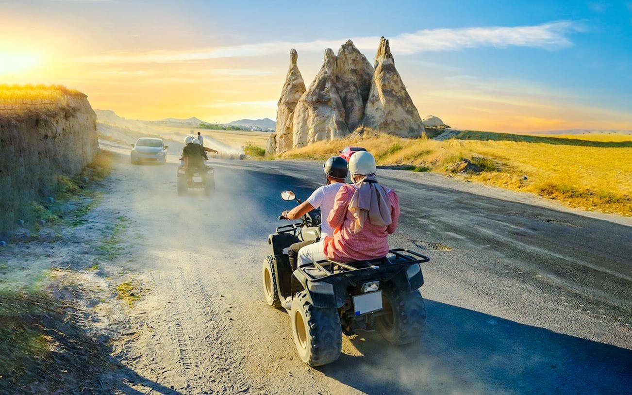 ATV riders exploring Cappadocia's unique rock formations at sunset.