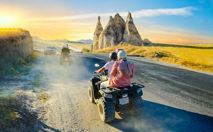 ATV riders exploring Cappadocia's unique rock formations at sunset.
