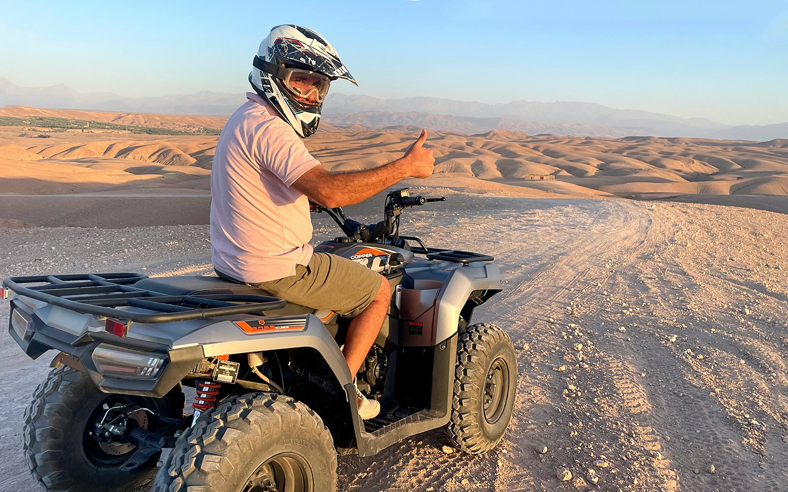 Quad biker giving thumbs up in Agafay Desert during guided tour.