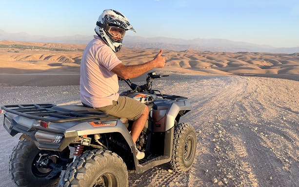 Quad biker giving thumbs up in Agafay Desert during guided tour.
