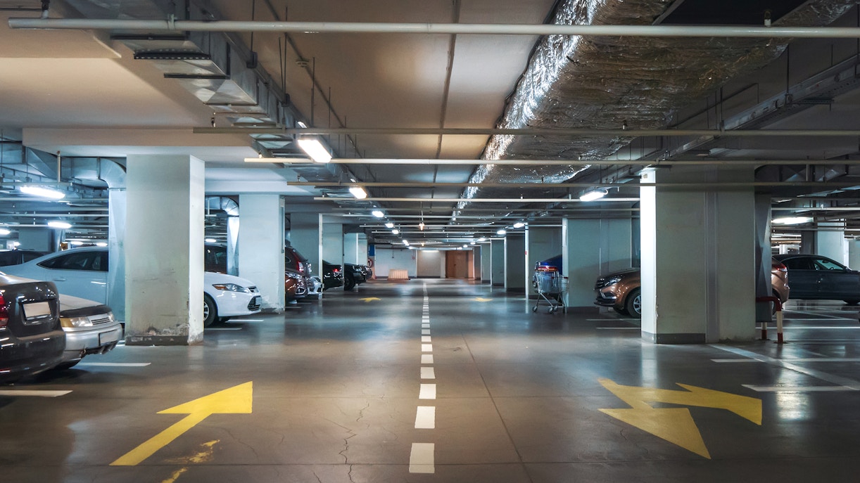 Underground parking garage with parked cars and directional arrows.