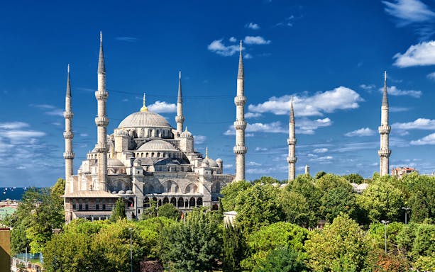 Blue Mosque exterior with minarets in Istanbul, surrounded by trees under a clear sky.