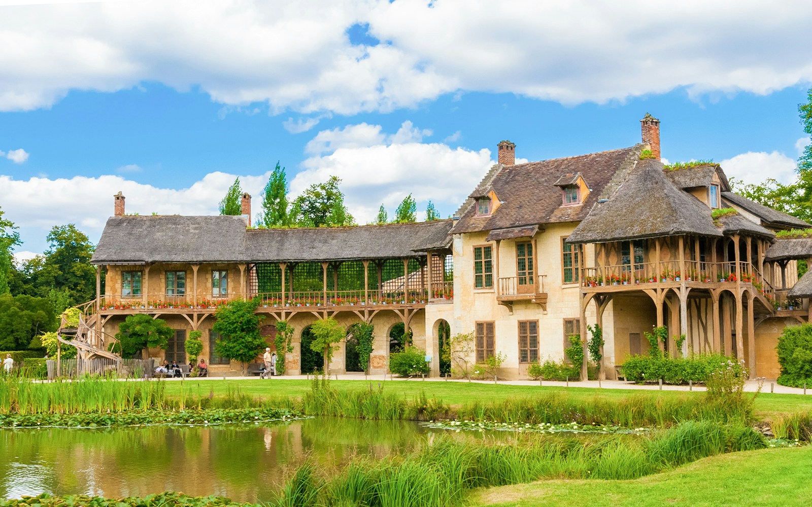 Marie Antoinette's Hamlet at Versailles Palace with rustic cottages and tranquil pond.