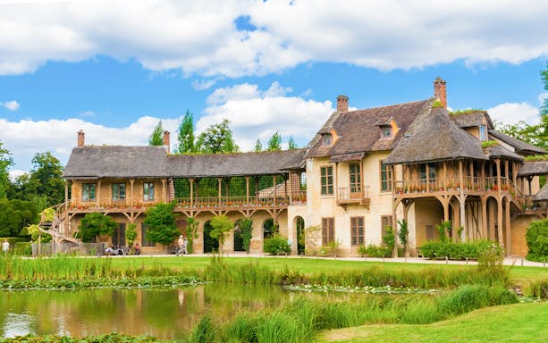Marie Antoinette's Hamlet at Versailles Palace with rustic cottages and tranquil pond.