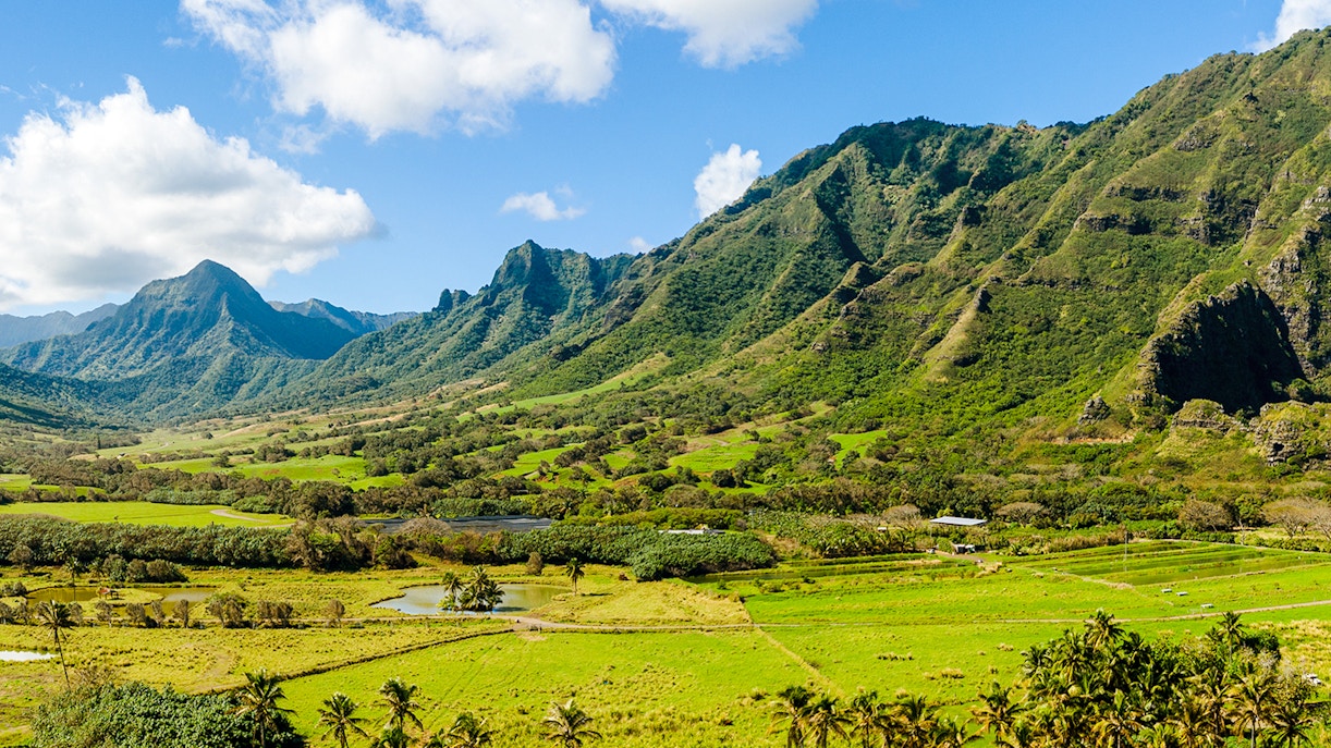 Wide panorama of lush green valleys and mountains at Kualoa Ranch, Oahu, Hawaii.