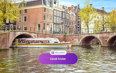 Canal cruise boat on Amsterdam canal with historic buildings and bridge.