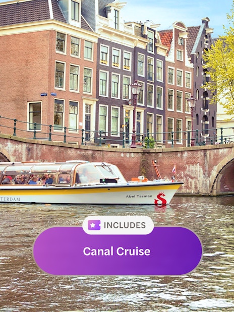 Canal cruise boat on Amsterdam canal with historic buildings and bridge.