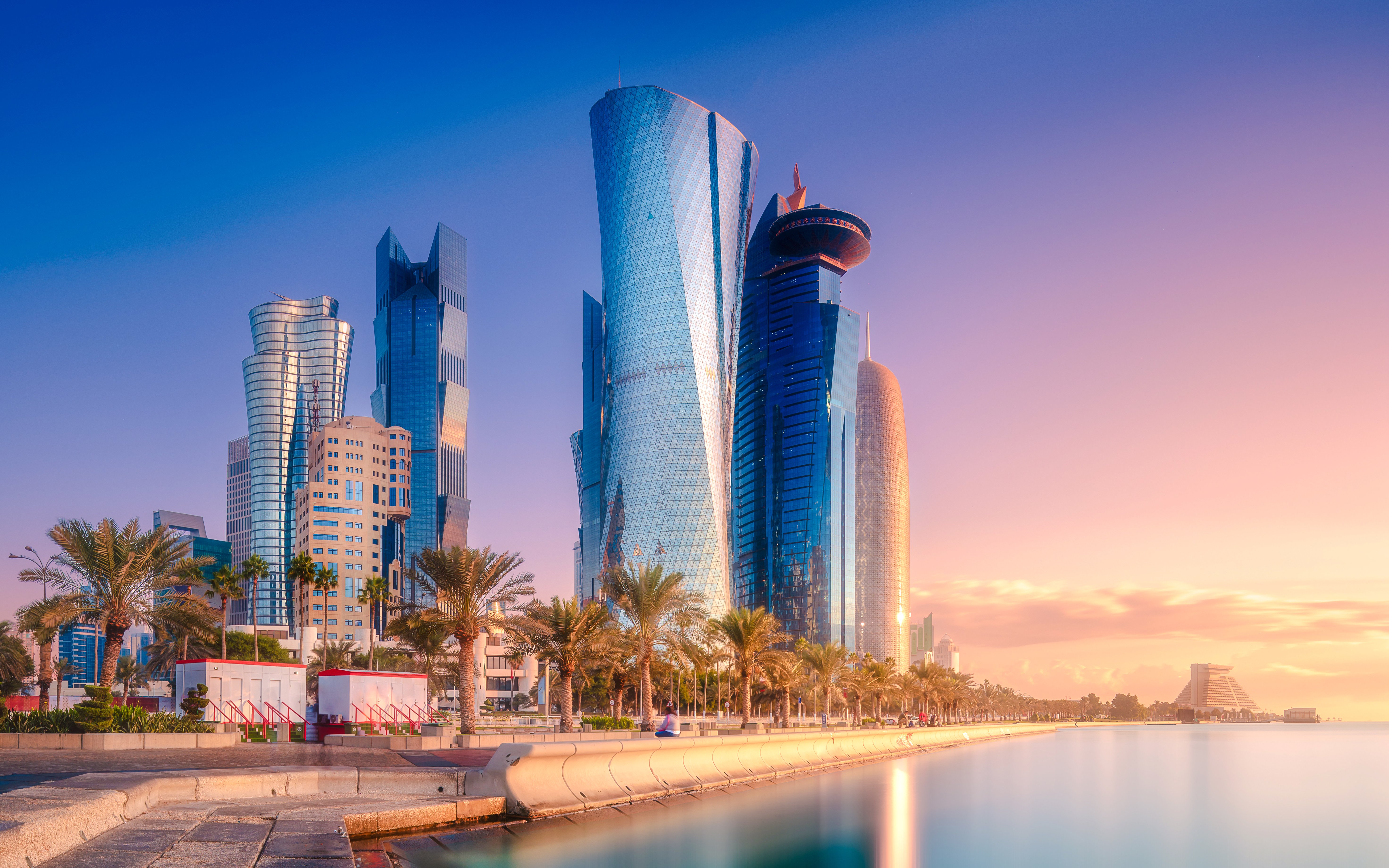 Skyline of West Bay and Doha City Center, Qatar, with modern skyscrapers at sunset.