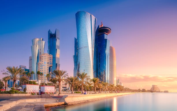 Skyline of West Bay and Doha City Center, Qatar, with modern skyscrapers at sunset.