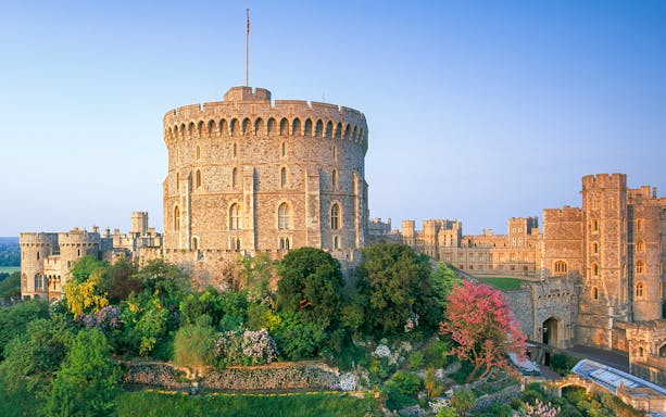 Round Tower at Windsor Castle surrounded by lush gardens, England.