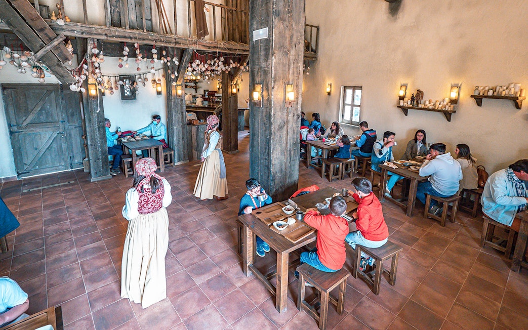 Visitors dining in a rustic medieval-themed restaurant at Puy du Fou España.