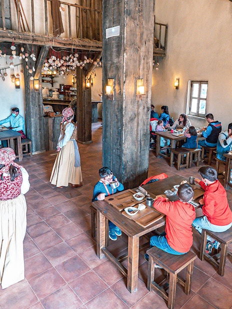 Visitors dining in a rustic medieval-themed restaurant at Puy du Fou España.