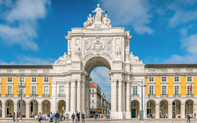 Arco da Rua Augusta in Praça do Comércio, Lisbon, Portugal with people walking.