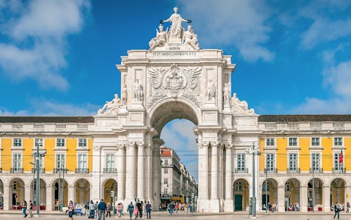 Arco da Rua Augusta in Praça do Comércio, Lisbon, Portugal with people walking.