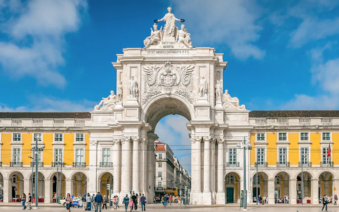Arco da Rua Augusta in Praça do Comércio, Lisbon, Portugal with people walking.
