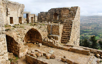 Jerash & Ajloun Castle ruins with stone arches and walls, view of Amman landscape.