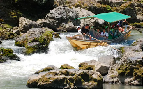 Boat navigating rapids on Hozugawa River during Kyoto day tour.