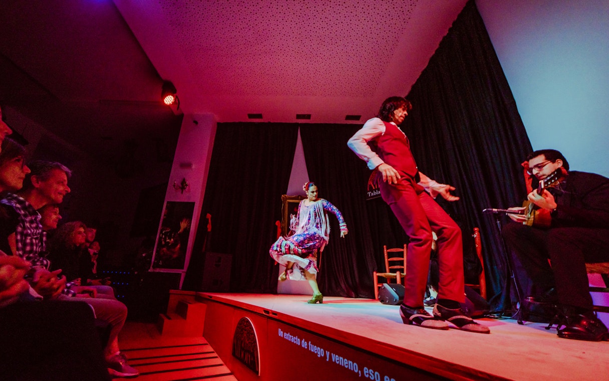 Flamenco dancers performing on stage at La Alboreá, Granada, with a guitarist playing.