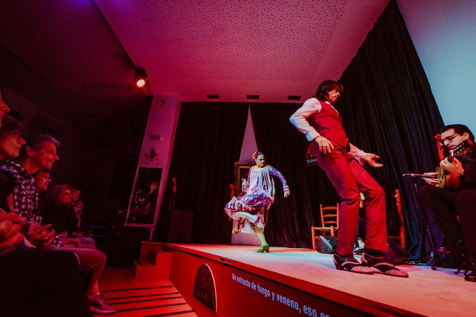 Flamenco dancers performing on stage at La Alboreá, Granada, with a guitarist playing.