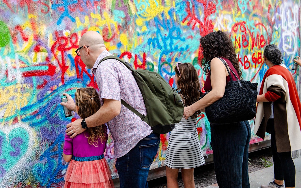 Visitors spray painting a colorful mural at Wynwood Walls Museum.