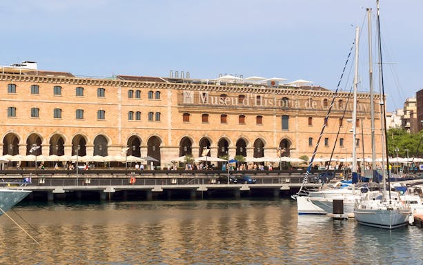 History Museum of Catalonia building with waterfront and docked sailboats.