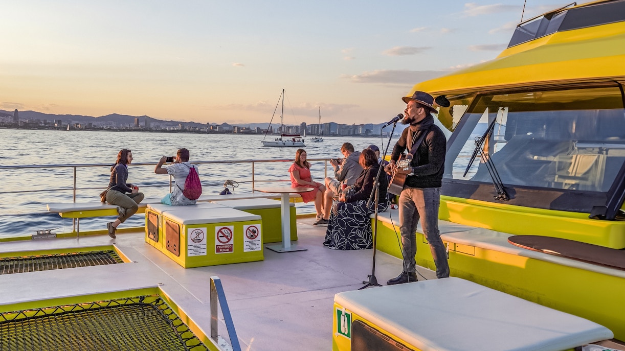 Catamaran sailing on the Mediterranean Sea with Barcelona skyline in the background.
