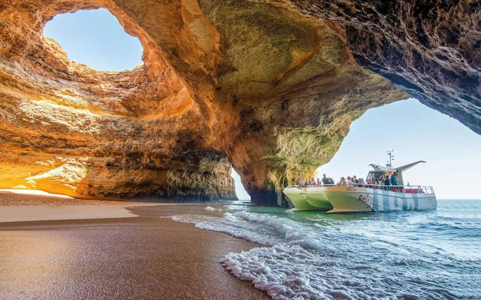 Catamaran with tourists exploring Benagil Caves in Algarve, Portugal.