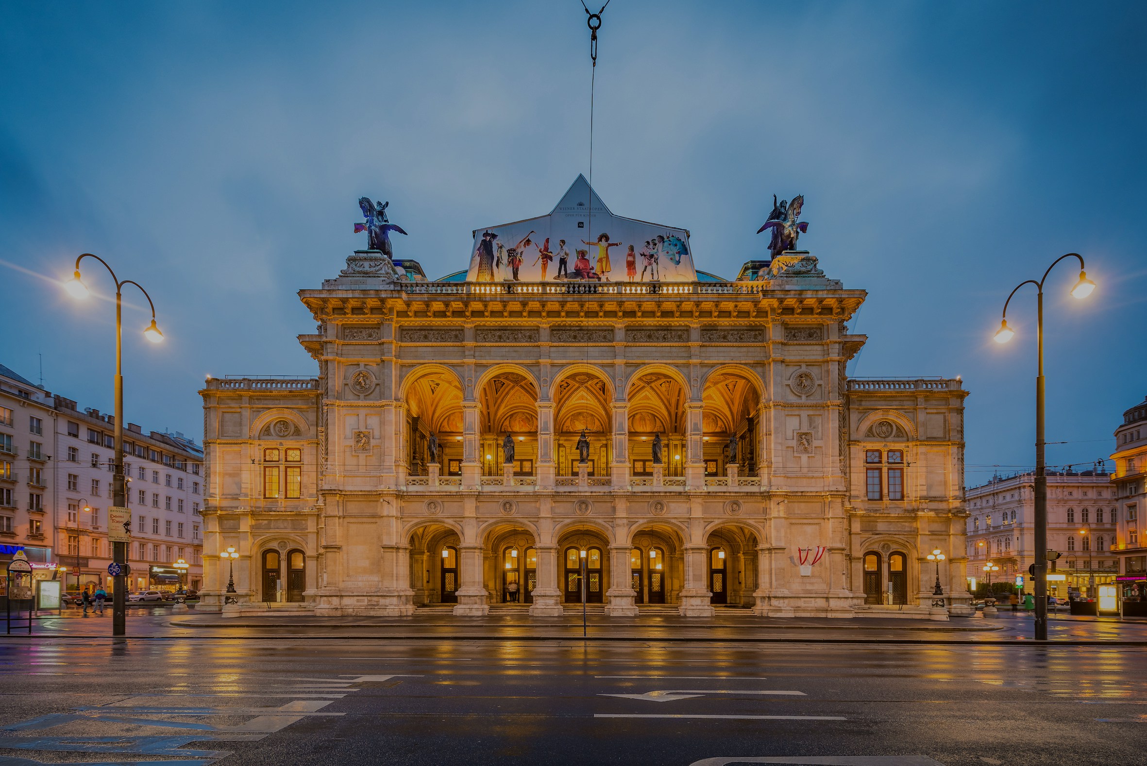 Vienna State Opera illuminated at dusk, showcasing its grand facade in Austria.