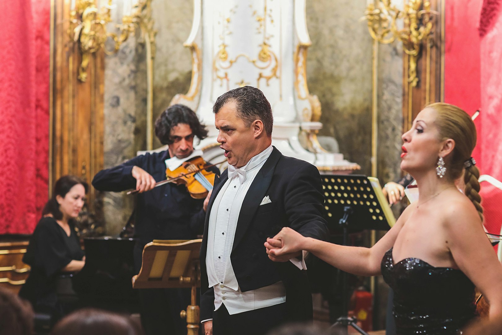 Vienna Baroque Orchestra performance with singers and violinist in ornate hall.