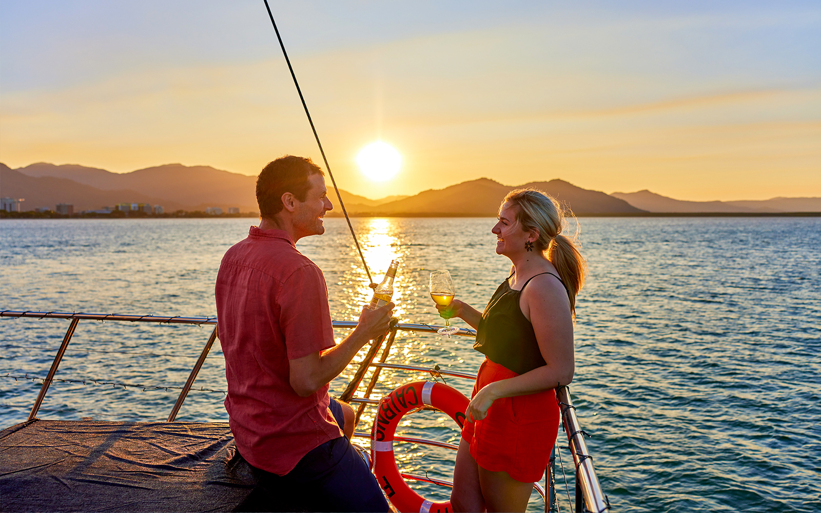 Couple toasting on Spirit of Cairns Dinner Cruise at sunset, Australia.