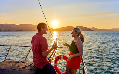 Couple toasting on Spirit of Cairns Dinner Cruise at sunset, Australia.