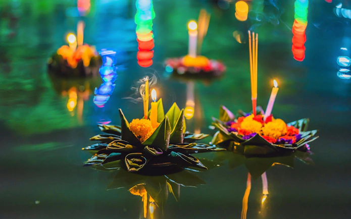 Floating flower arrangements with candles during Loy Krathong Festival in Thailand.