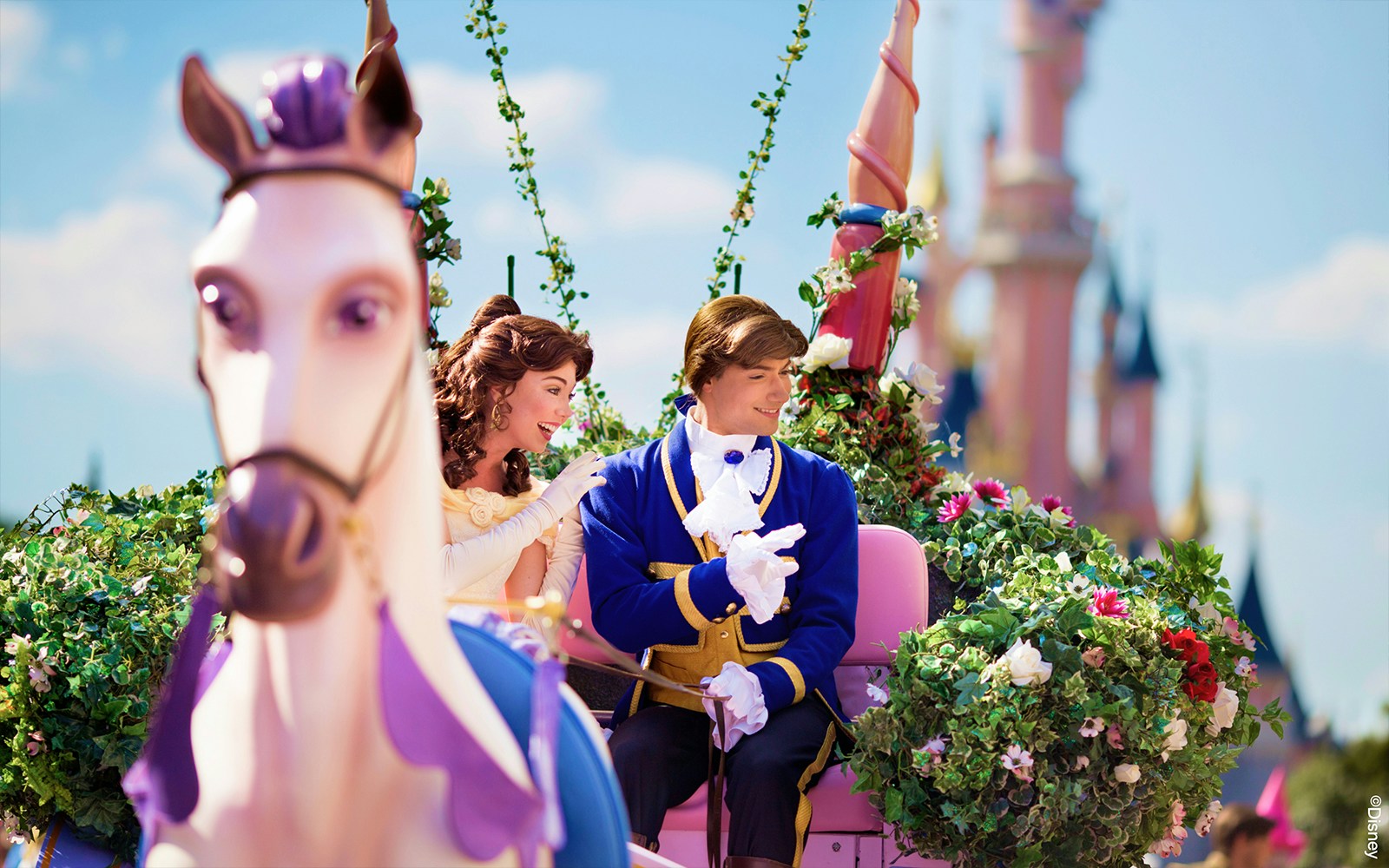 Belle and prince on a floral float during Disneyland Paris parade.