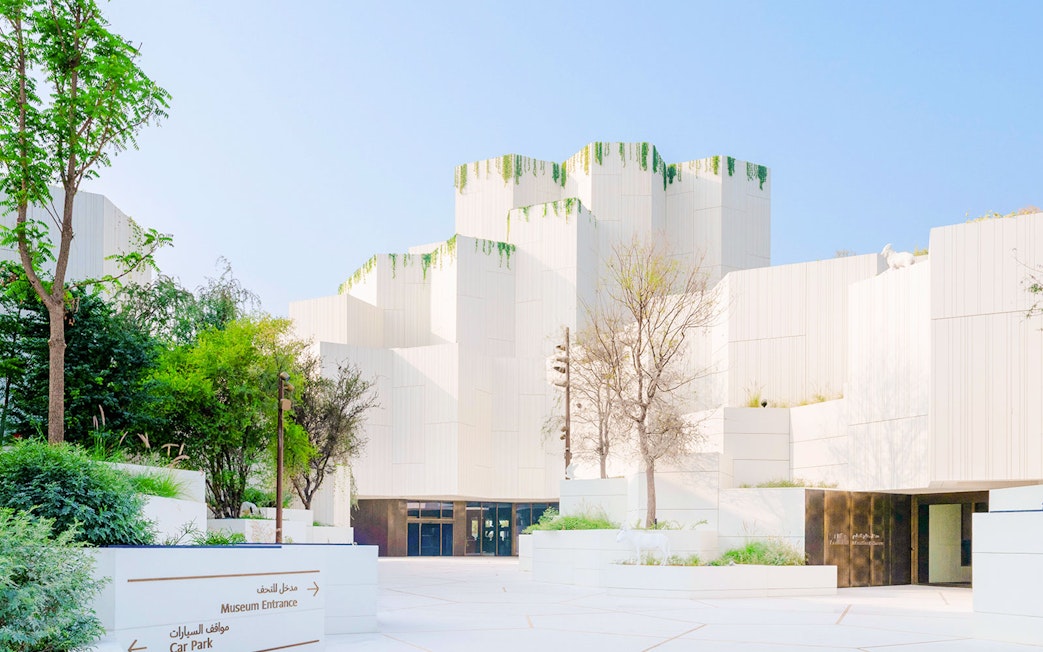 Exterior view of the Natural History Museum with modern white architecture and greenery.