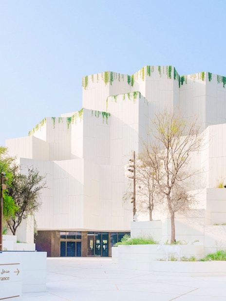 Exterior view of the Natural History Museum with modern white architecture and greenery.