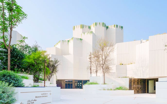 Exterior view of the Natural History Museum with modern white architecture and greenery.