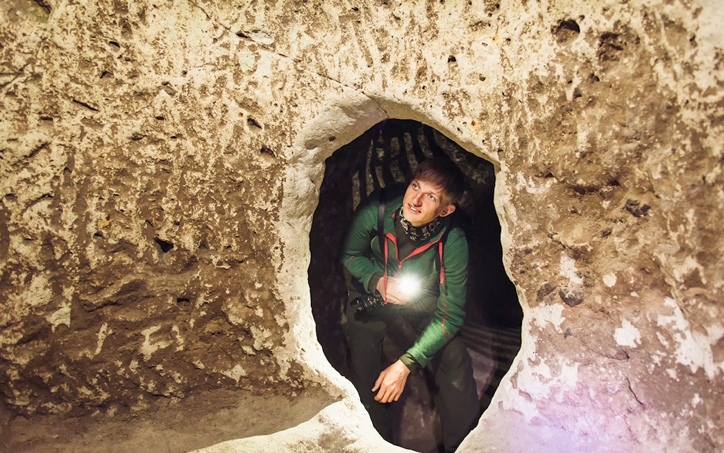 Tourist exploring Derinkuyu underground cave city with flashlight.