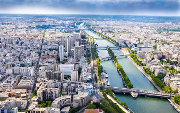 Aerial view of Paris with the Seine River and cityscape, highlighting landmarks on a guided tour.