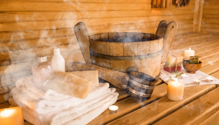 Sauna interior with wooden benches and hot stones, highlighting relaxation in a park setting.