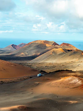 Tour bus traversing volcanic landscape in Timanfaya National Park, Lanzarote.