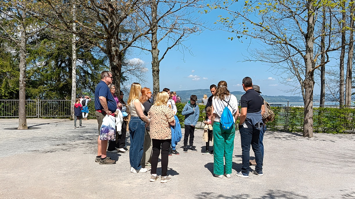Tour group gathered outside Neuschwanstein Castle, surrounded by trees and scenic views.