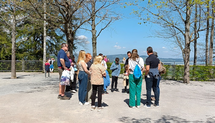 Tour group gathered outside Neuschwanstein Castle, surrounded by trees and scenic views.