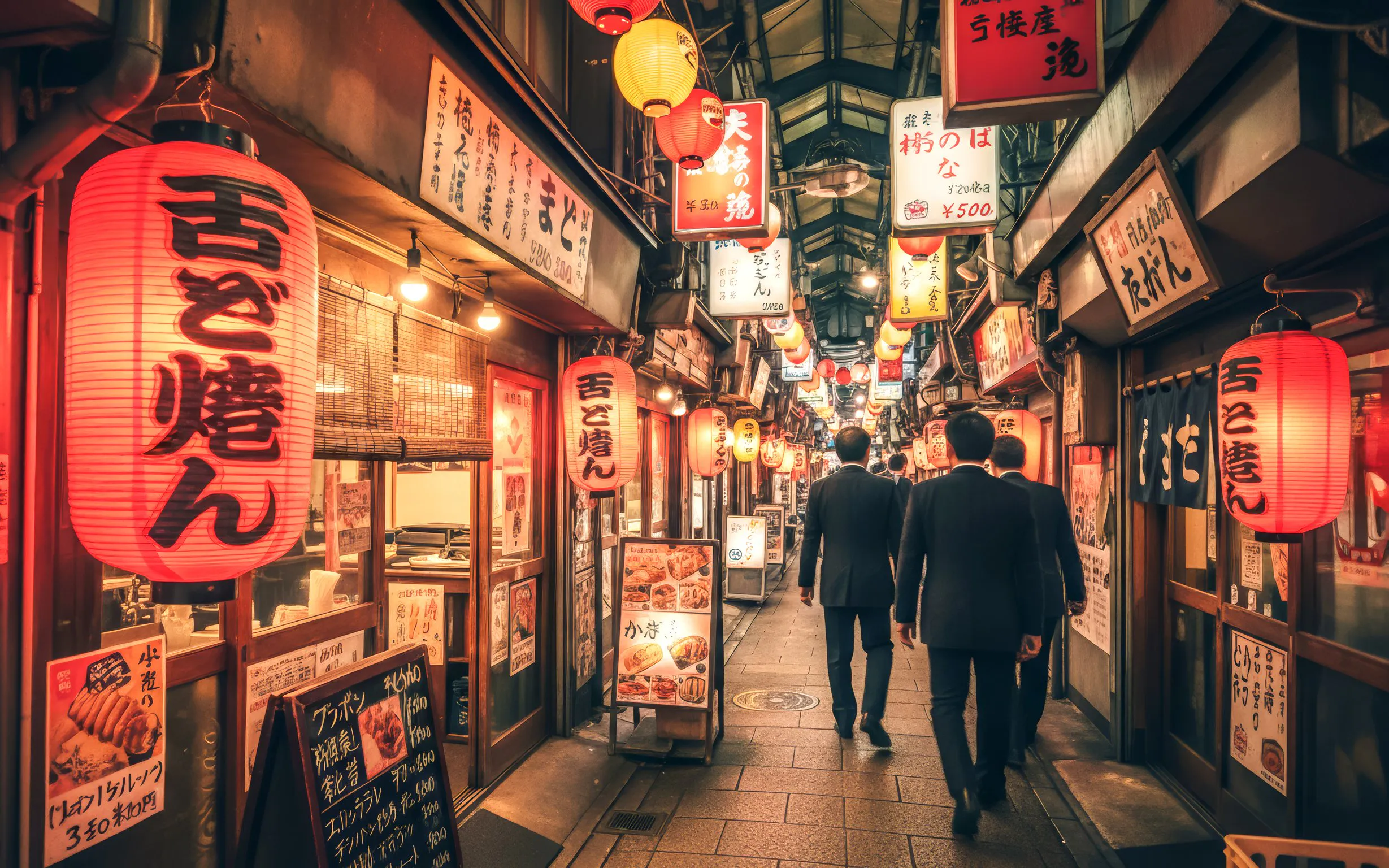 Alley in Osaka with lanterns and signs during night food tour.