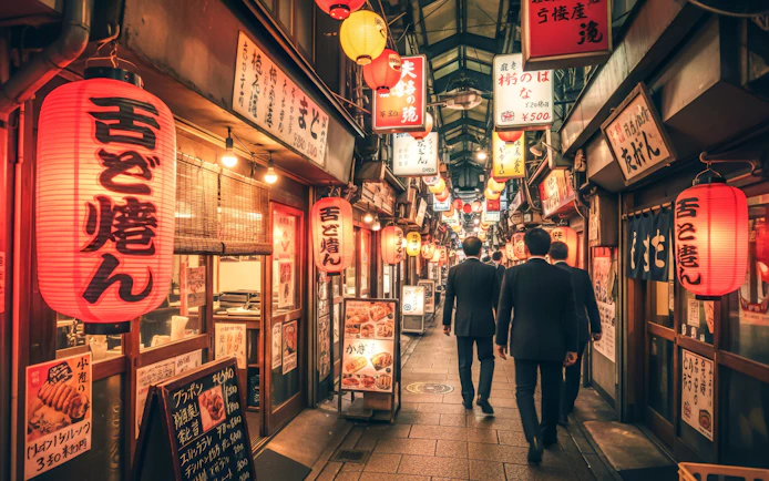 Alley in Osaka with lanterns and signs during night food tour.