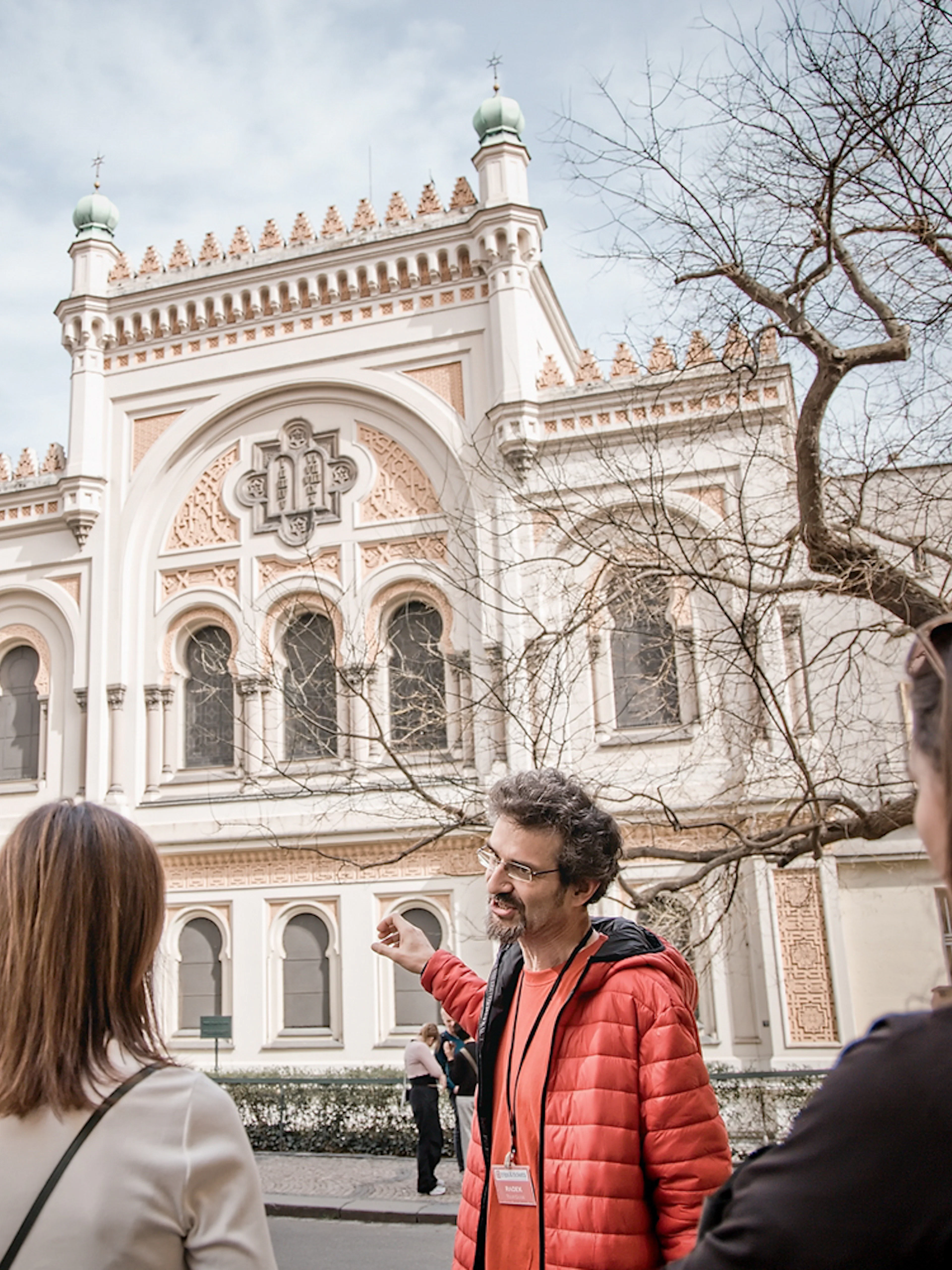 Tour guide explaining the Spanish Synagogue to visitors in Prague's Jewish Ghetto.