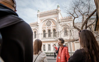 Tour guide explaining the Spanish Synagogue to visitors in Prague's Jewish Ghetto.