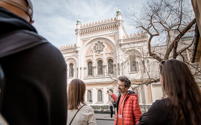 Tour guide explaining the Spanish Synagogue to visitors in Prague's Jewish Ghetto.
