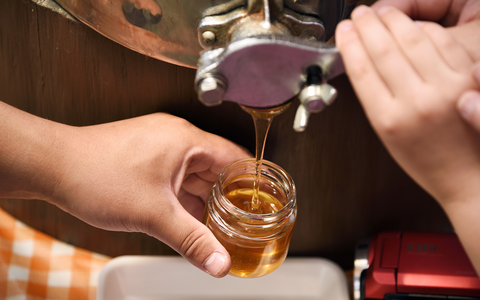 Bottling freshly harvested honey into a jar from a spout.