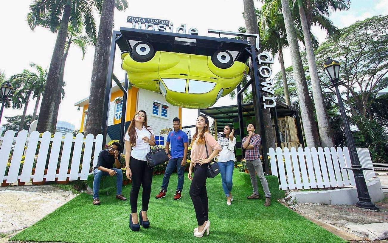 Visitors outside Kuala Lumpur Upside Down House with an inverted car display.