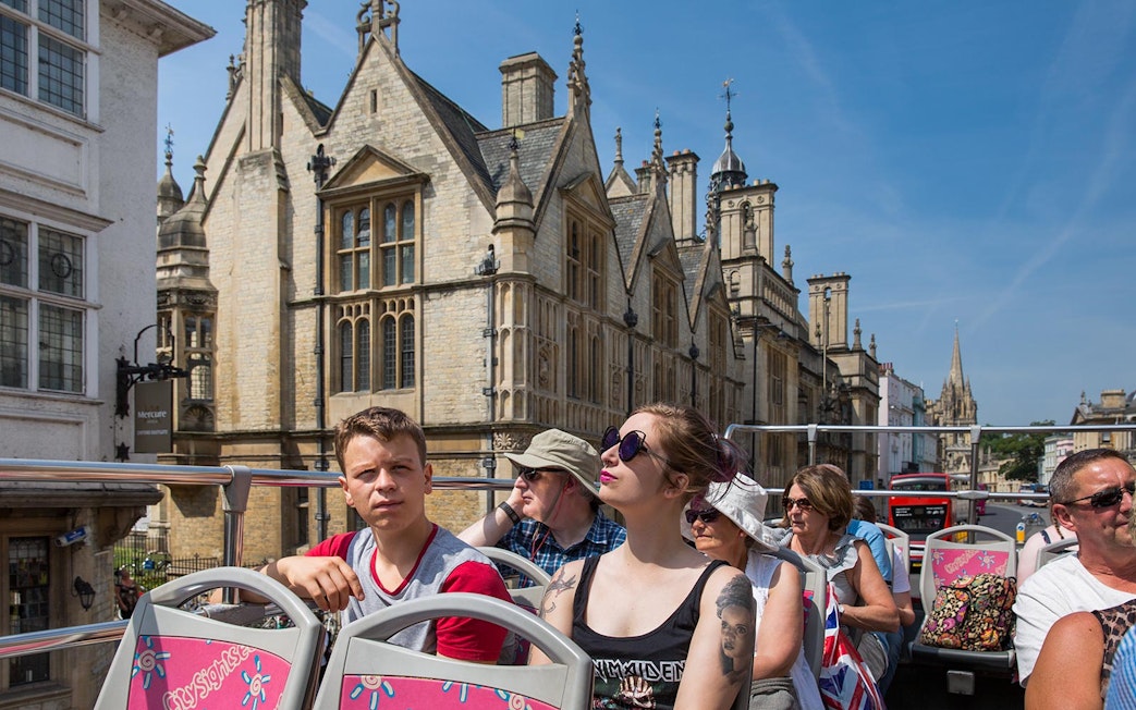 Open-top bus tour in Oxford with historic architecture in the background.
